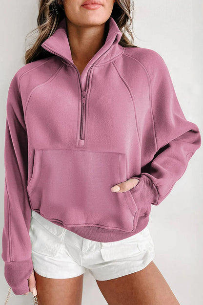 Person wearing a pink half-zip sweatshirt and white shorts on a light gray background