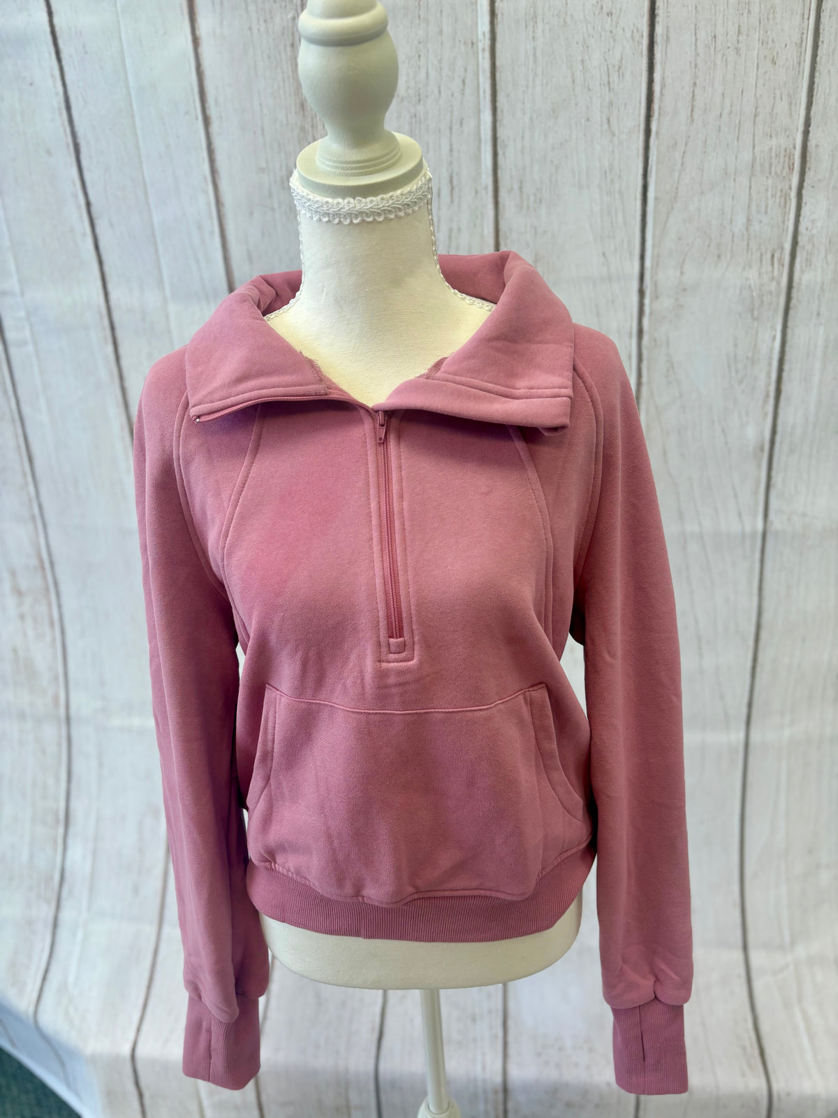 Pink pullover on a mannequin against a wooden panel background