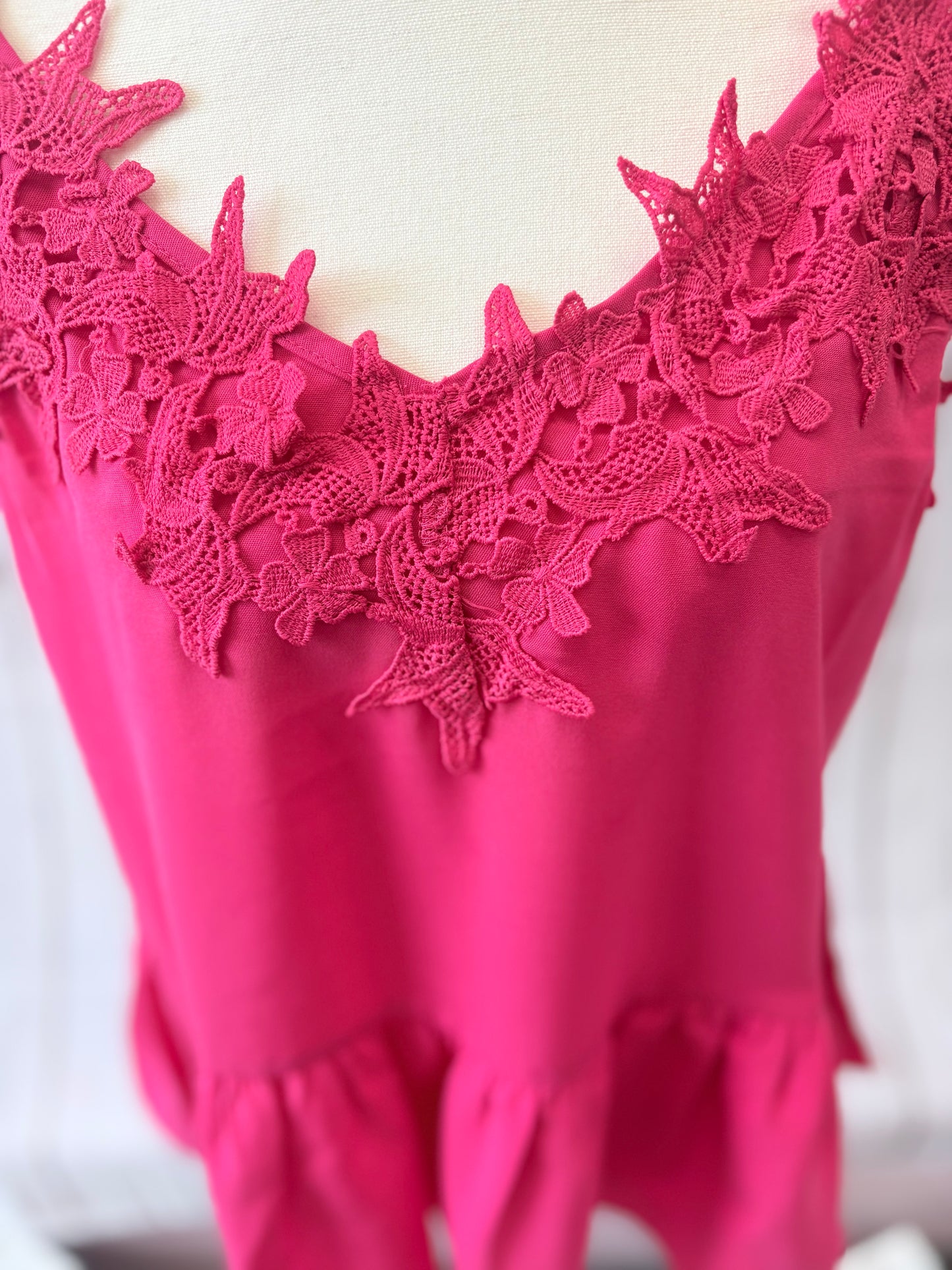 Close-up of a pink lace-trimmed top on a white background