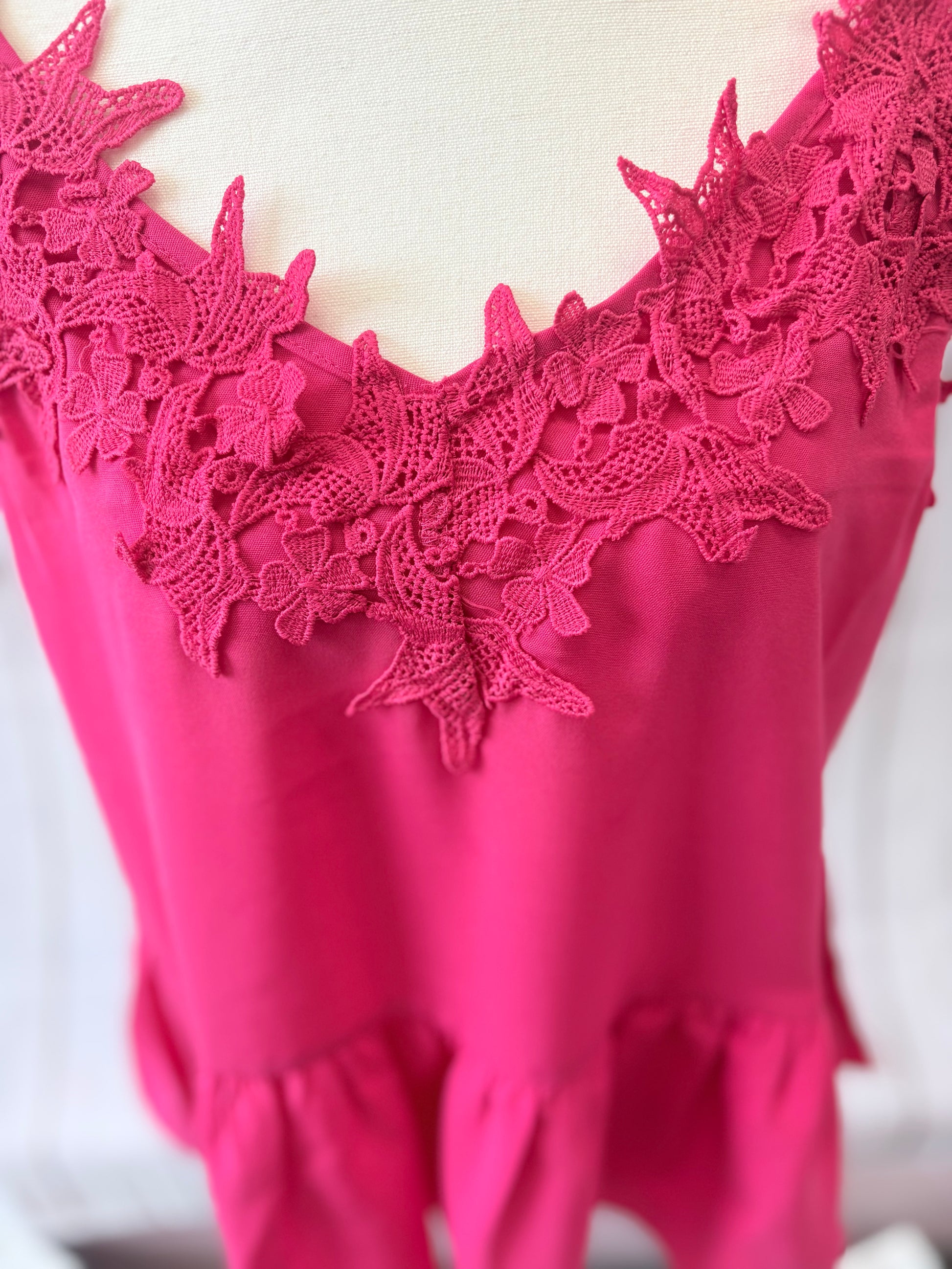 Close-up of a pink lace-trimmed top on a white background