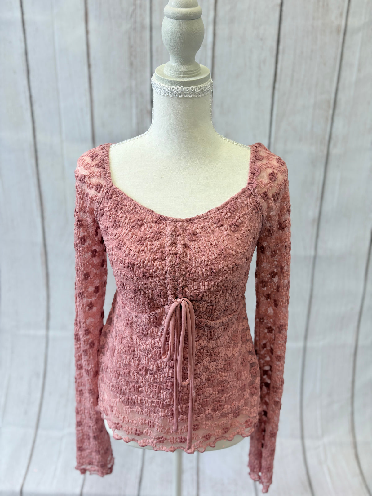 Pink textured top on a mannequin against a light wooden panel background