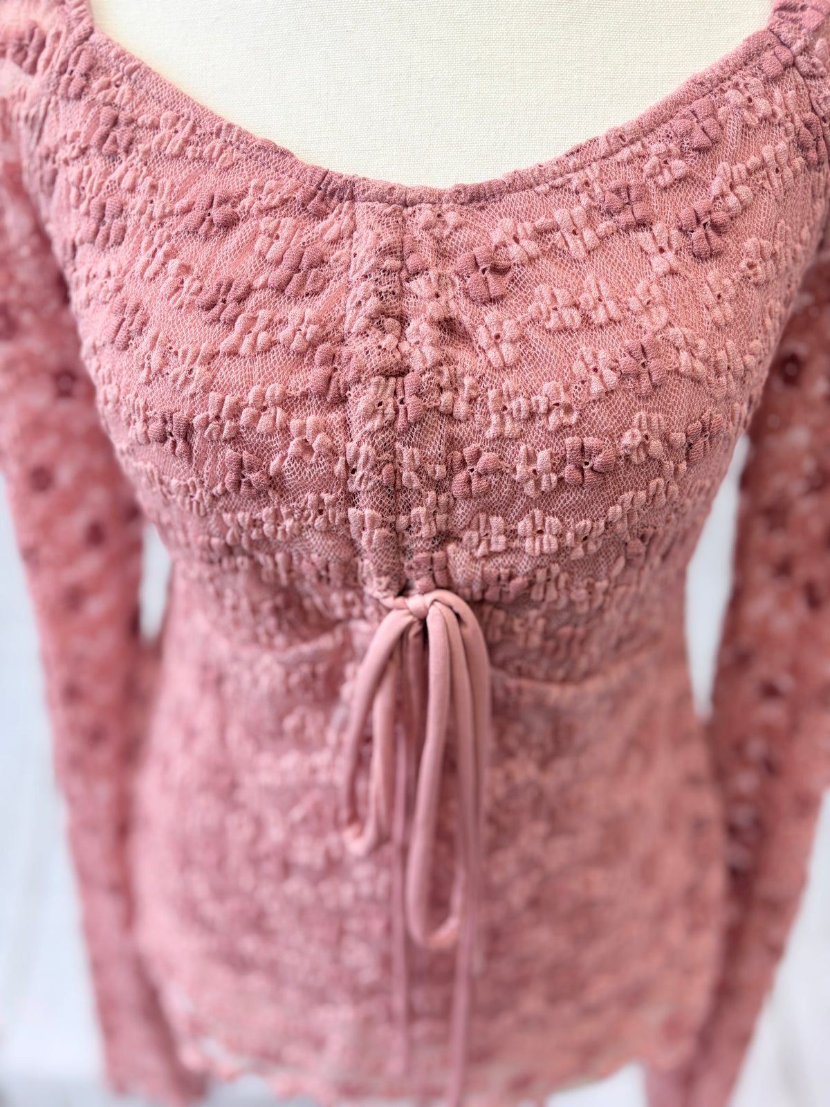 Pink textured top on a mannequin with a blurred background