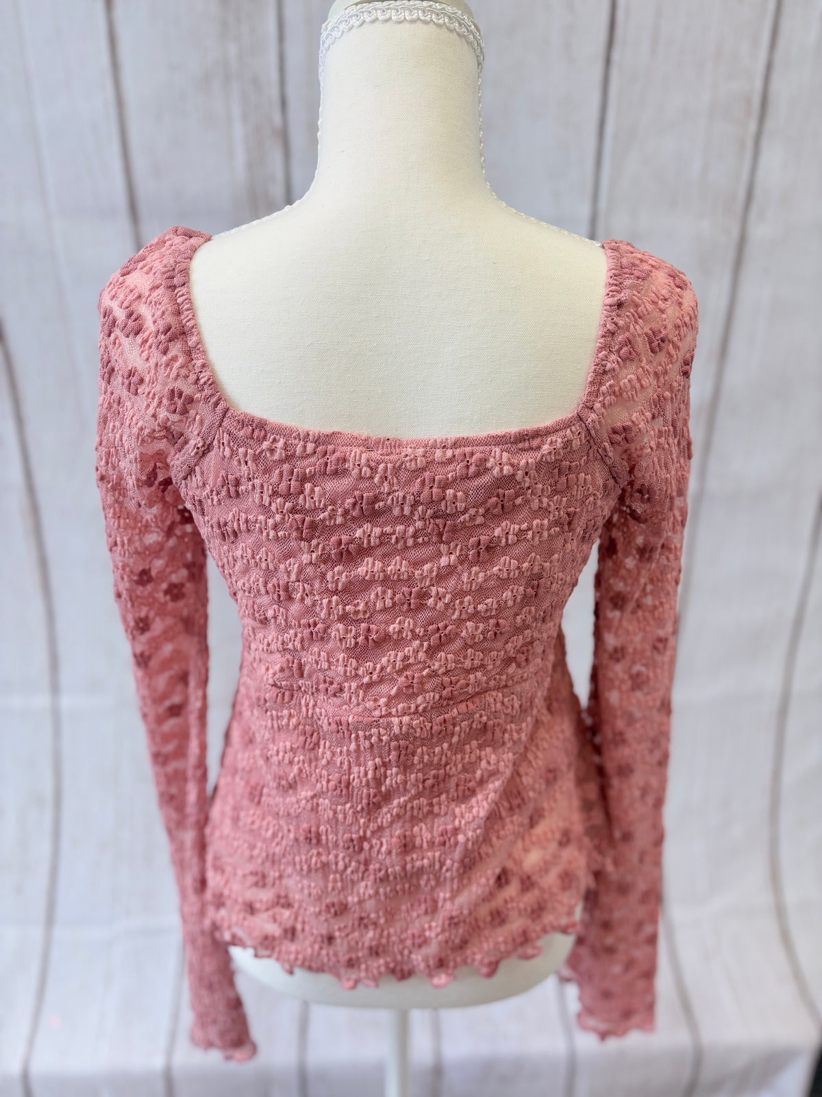 Pink textured long-sleeve top on a mannequin against a white background